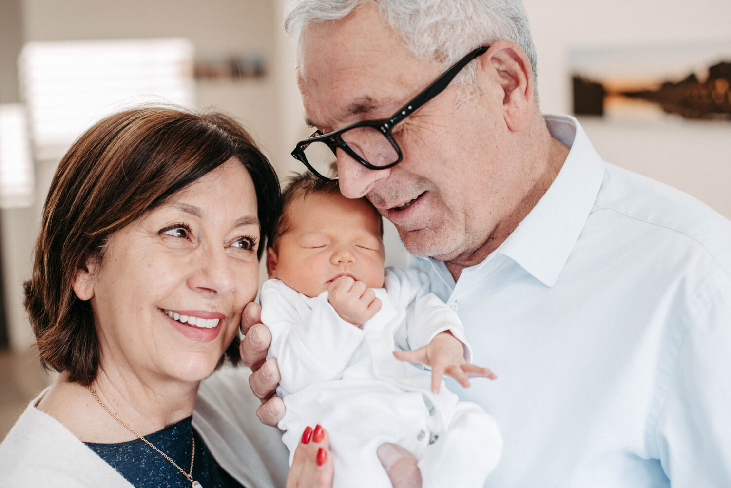 Oma und Opa halten ihr Enkelkind voller Glück und Zufriedenheit im Arm und sind überglücklich beim Fotoshooting in Alsfeld.